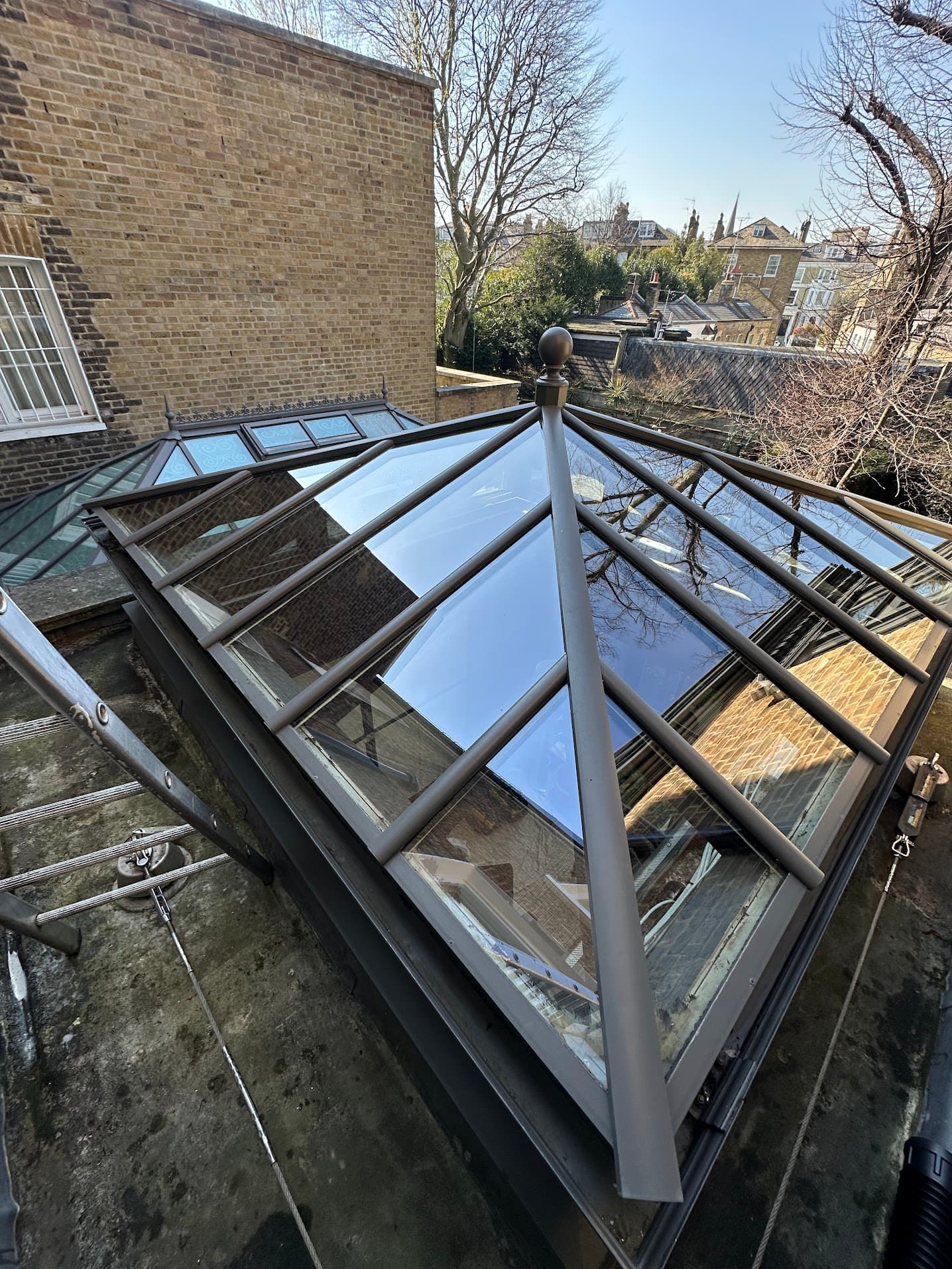 A freshly cleaned glazed roof lantern on a London townhouse, glass reflecting a clear blue sky.