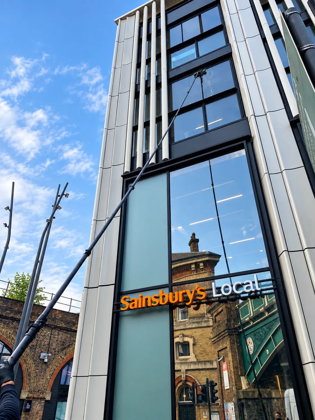 Reaching the upper floor of a shopfront building with a water-fed pole.