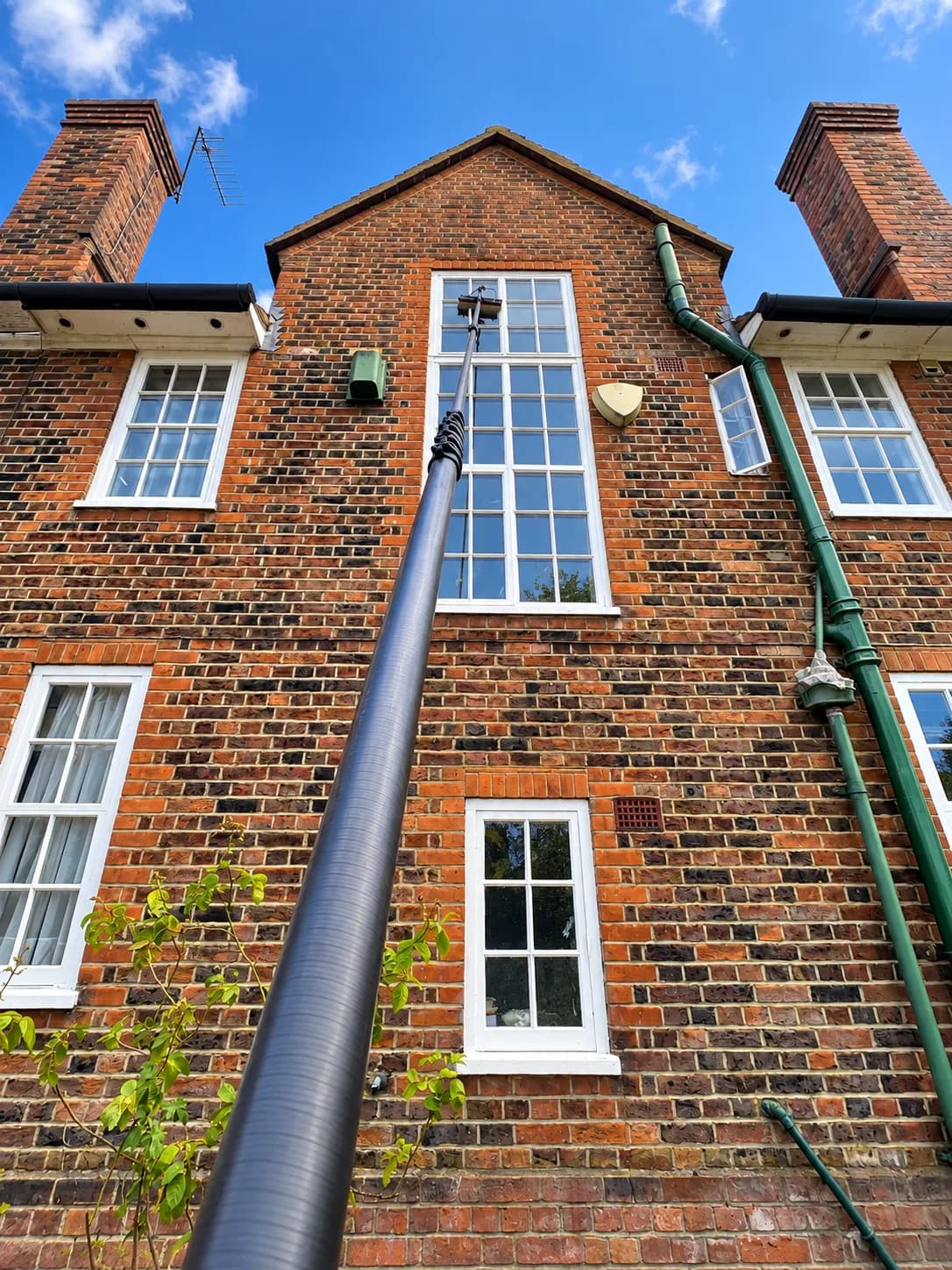 Reaching the top-floor windows of a red-brick house with a water-fed pole.