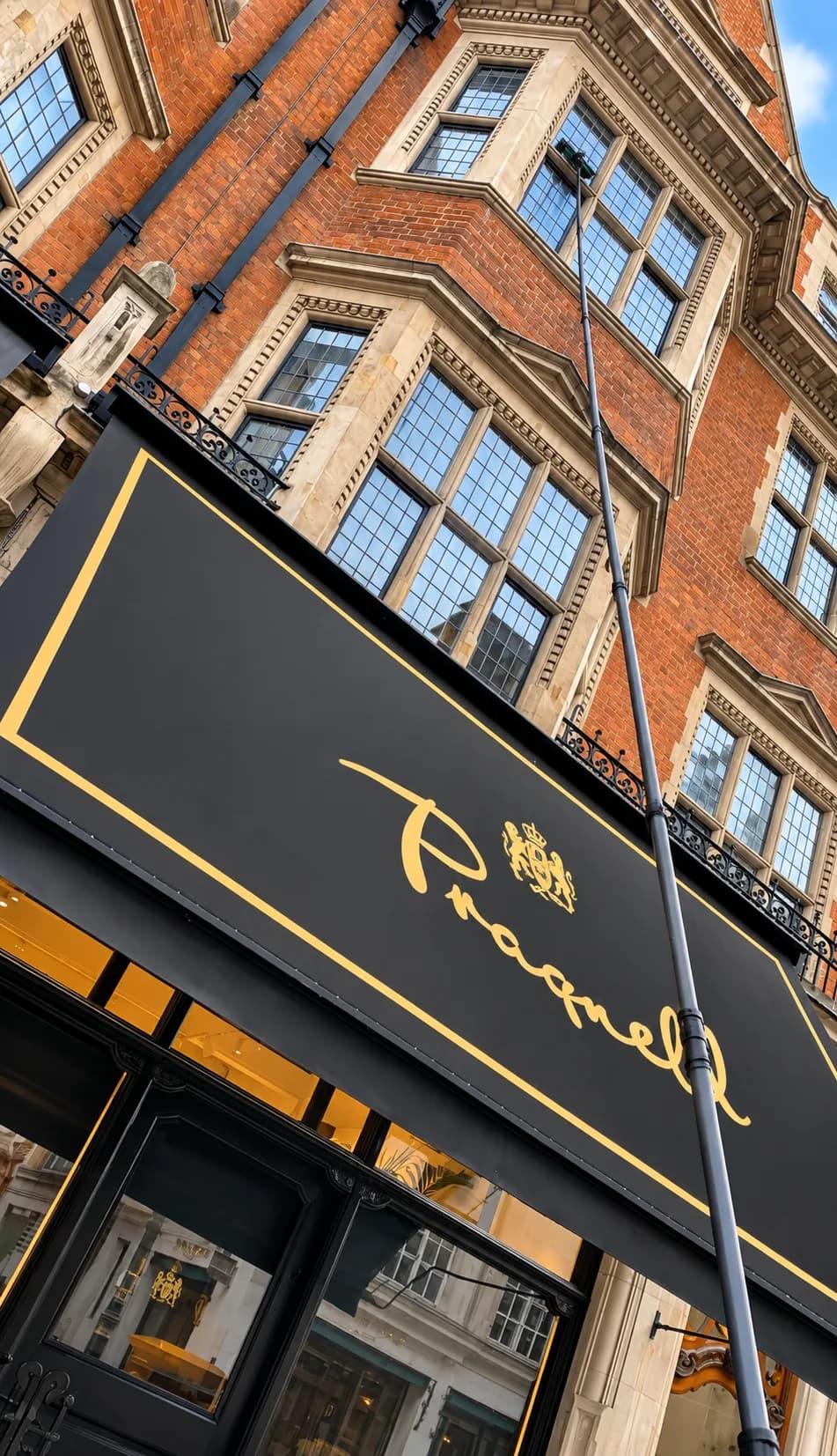 A water-fed pole reaching several storeys up a red-brick building above a shopfront awning.
